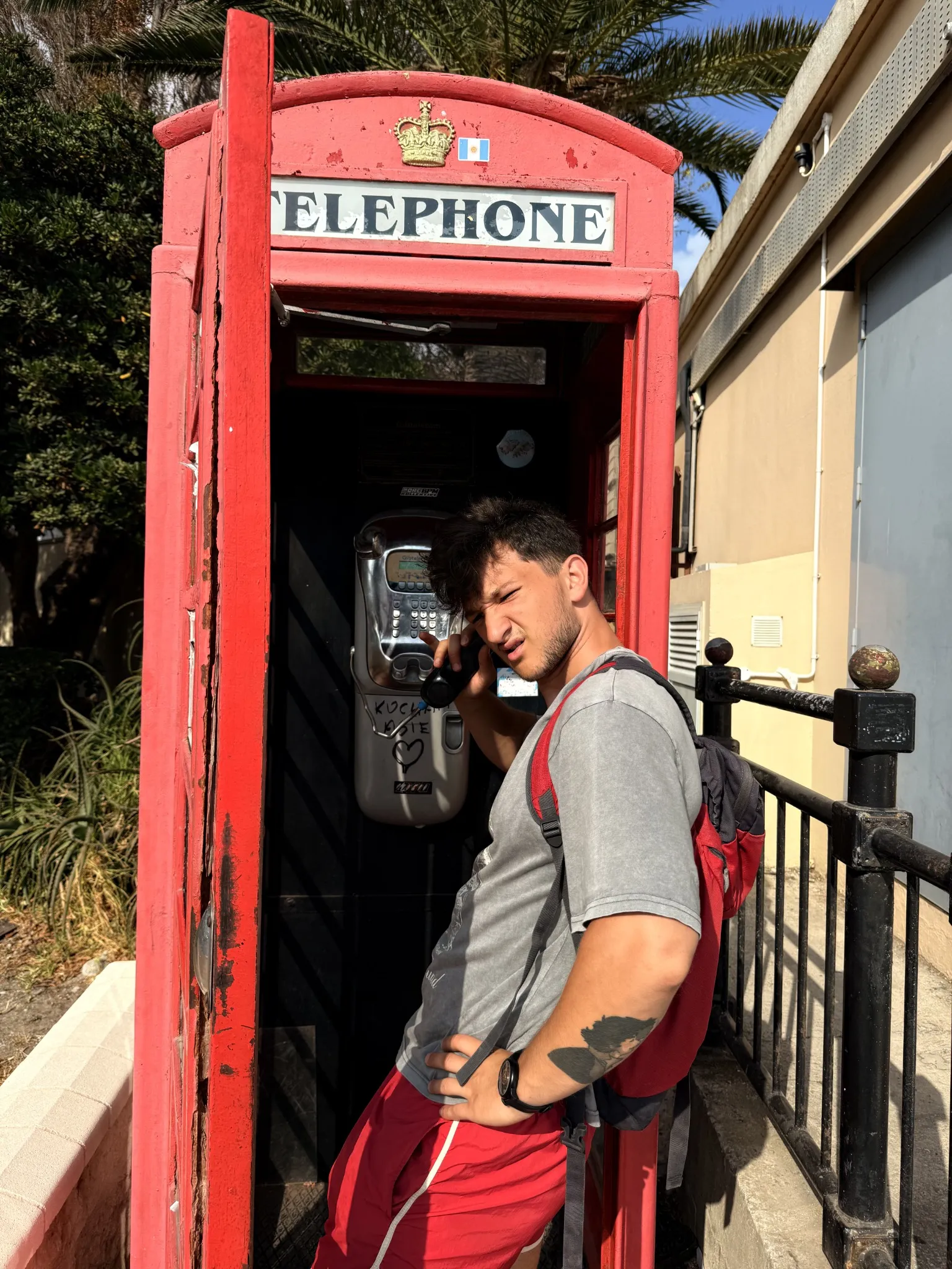 A traveller with a backpack beside a red telephone box