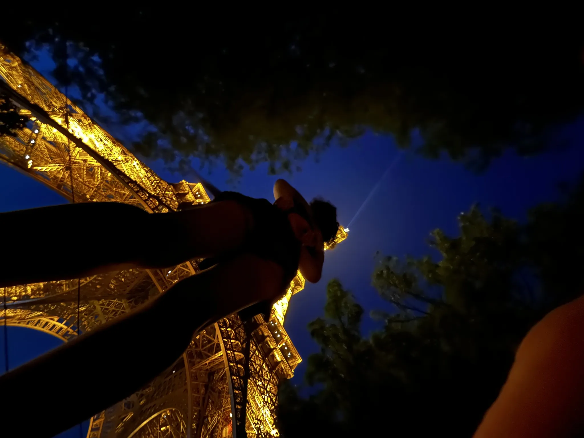 A low-angle night view beneath the illuminated Eiffel Tower