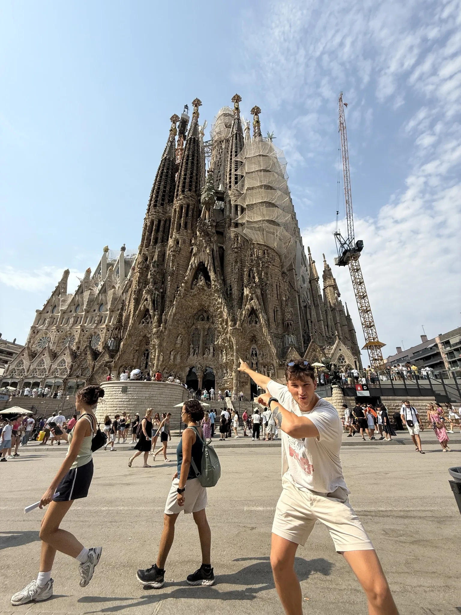 A traveller posing in front of the towers of the Sagrada Família